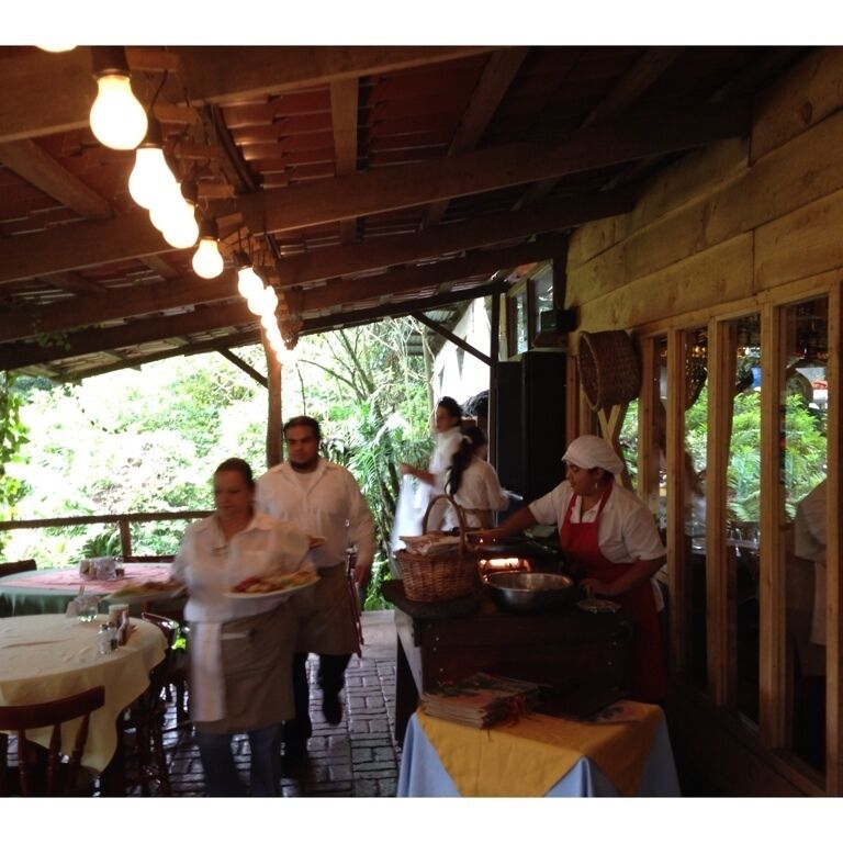 A rustic outdoor dining area with wooden beams and hanging light bulbs.