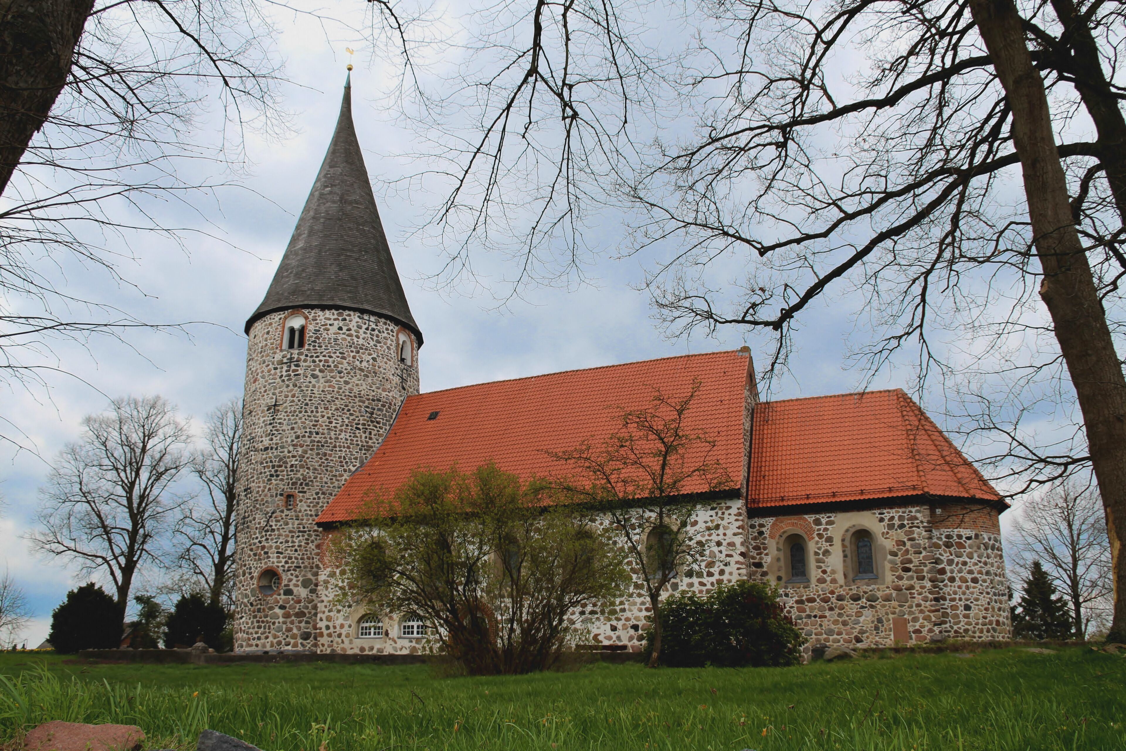 A church with a stone tower and a red-tiled roof.