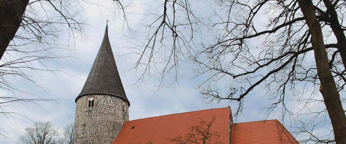 A church with a stone tower and a red-tiled roof.