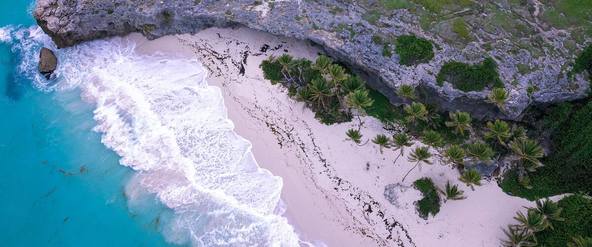 A coastal landscape with a sandy beach, rocky cliffs, and sparse vegetation.