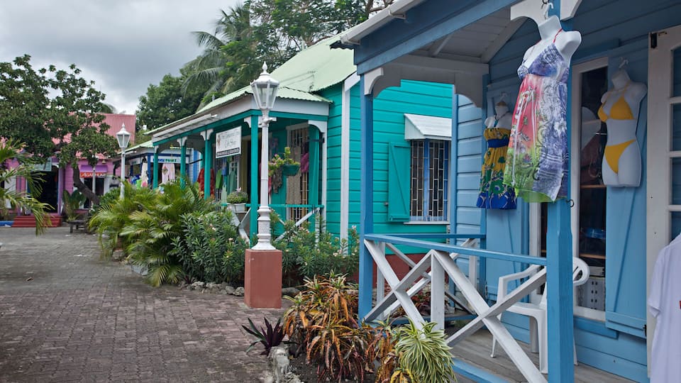 A colorful street with turquoise buildings, a white fence, and various shops.