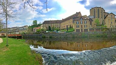 A historic building complex by a river with a small waterfall.