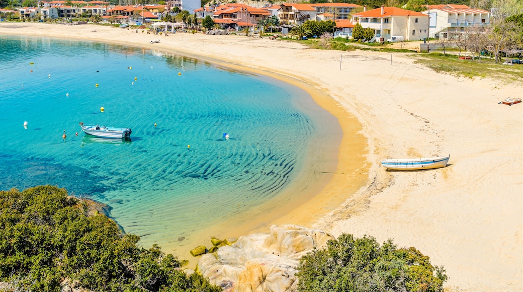 A coastal town with clear turquoise waters, sandy beaches, and red-roofed buildings.