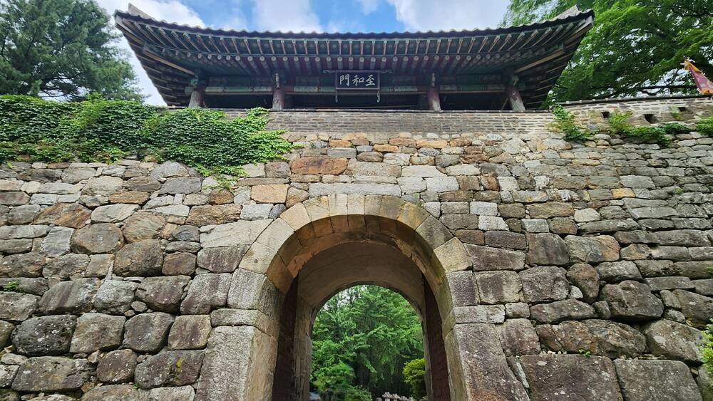 A traditional Korean gate with stone walls and a tiled roof.