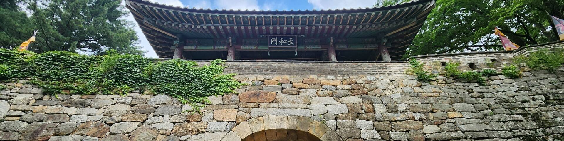A traditional Korean gate with stone walls and a tiled roof.