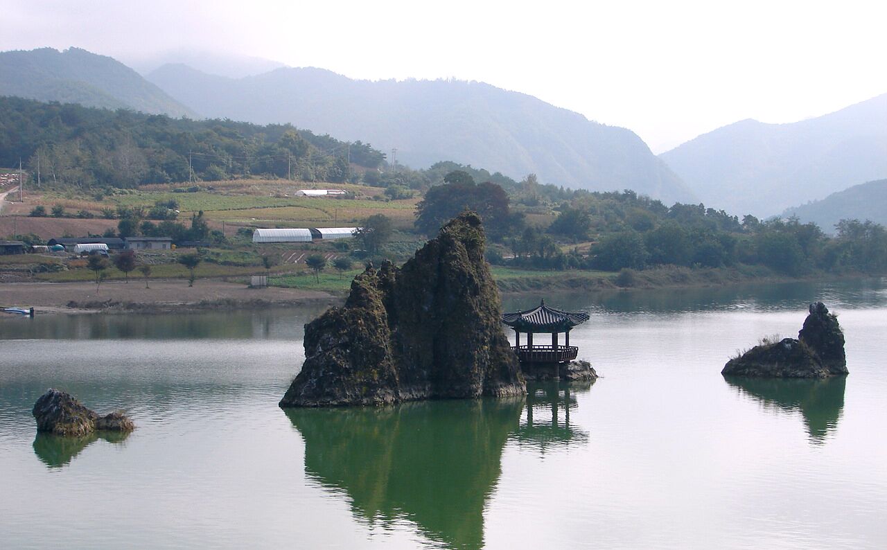 Dodam Sambong (3 Peak Island) represents the typical love triangle of ancient Korea: a husband, his wife and his mistress. The biggest peak, about 20 feet high with a pavilion on top, in the middle represents the husband, while the first smaller peak on one side of the husband is the wife. On the other side the smallest peak is the mistress. According to legend, the wife was not able to give birth to a son, so the husband found a mistress for a son. The wife was upset, which is why the wife peak is farther from the husband than the mistress. If you look at the wife from a specific angle and use a bit of imagination, you will see that the wife was so angry that she turned away from the husband.