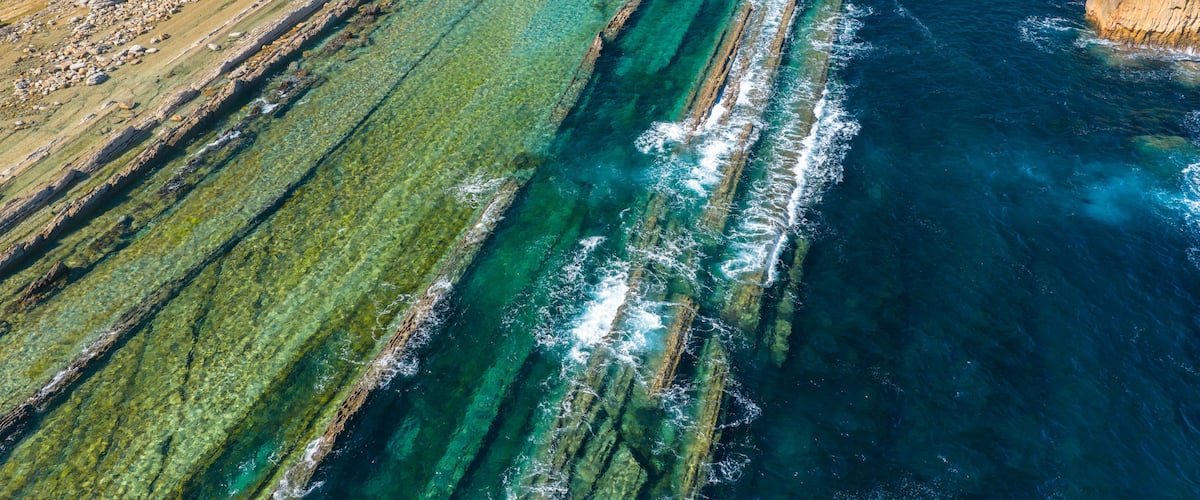 Aerial view of dramatic cliffs, sea stacks, and turquoise water along Costa Quebrada coastline, Cantabria, Northern Spain