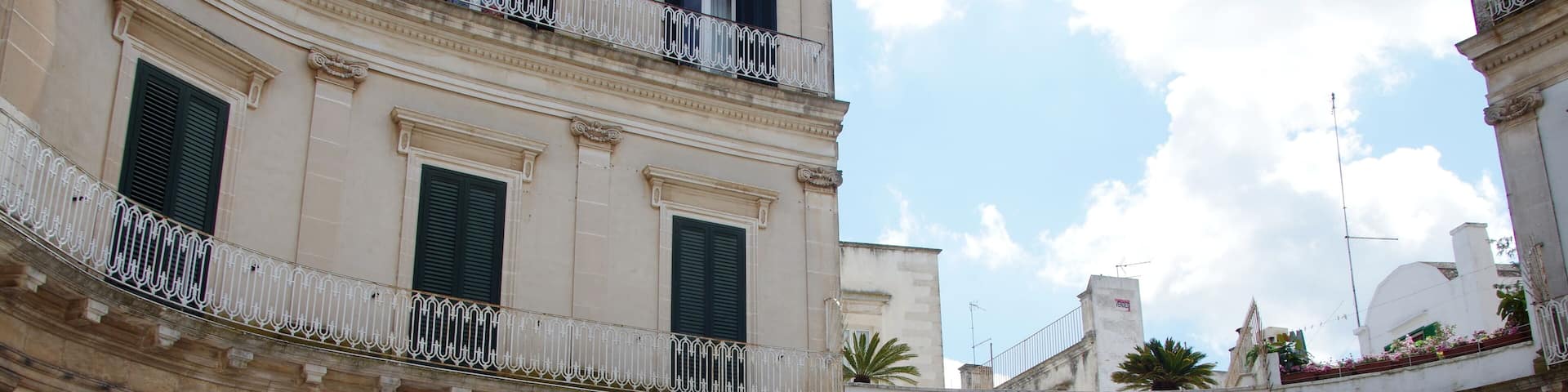 A historic courtyard with arches, outdoor seating, and potted plants.