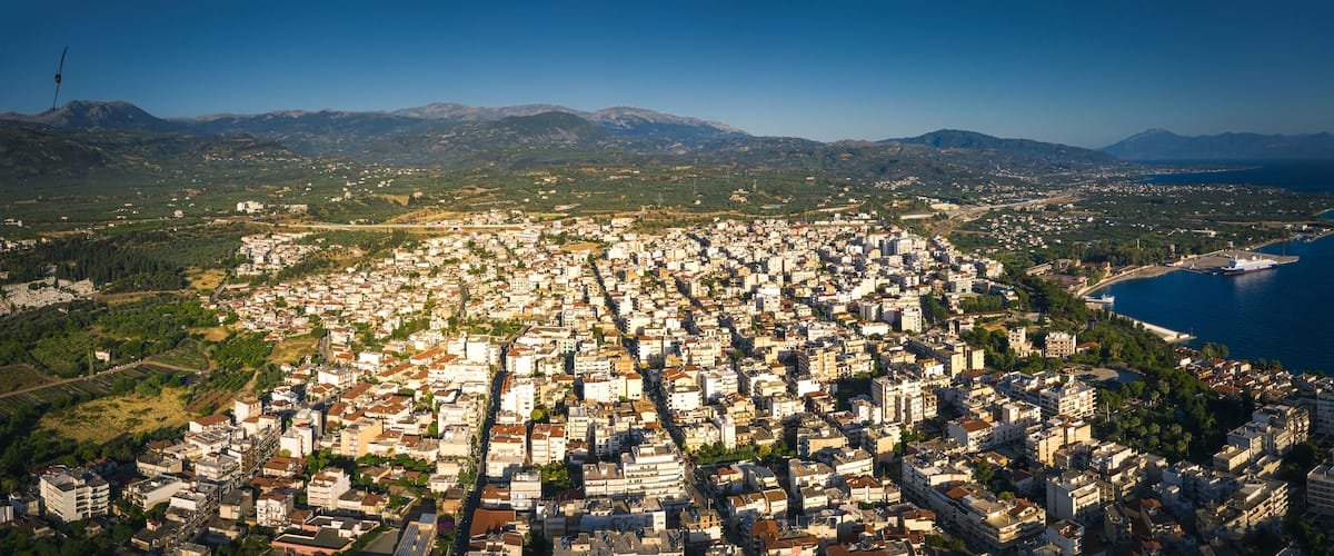 A coastal city with dense urban development, a port, and mountainous terrain in the background.