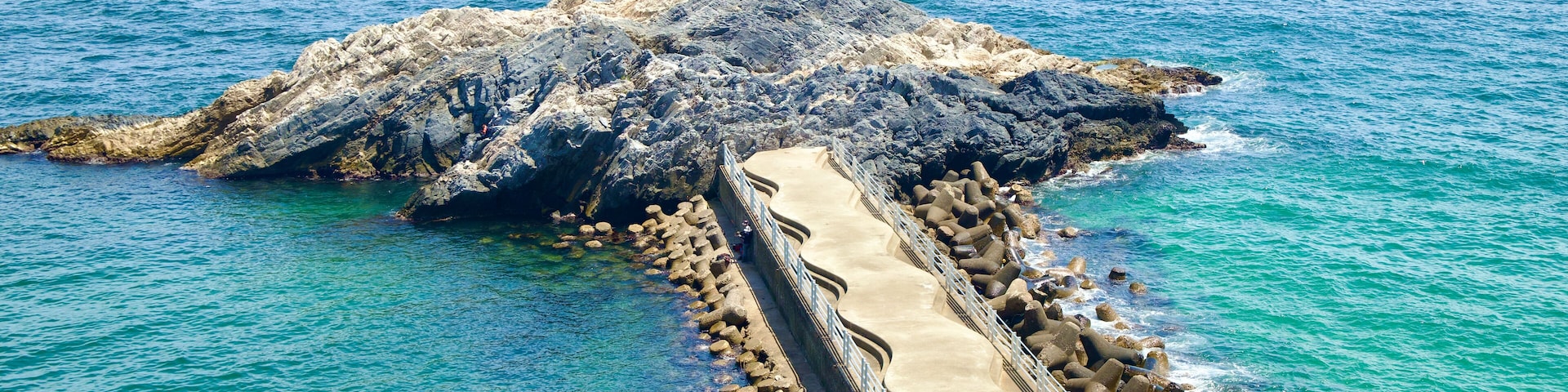 Un rompeolas rocoso que se extiende hacia aguas turquesas.