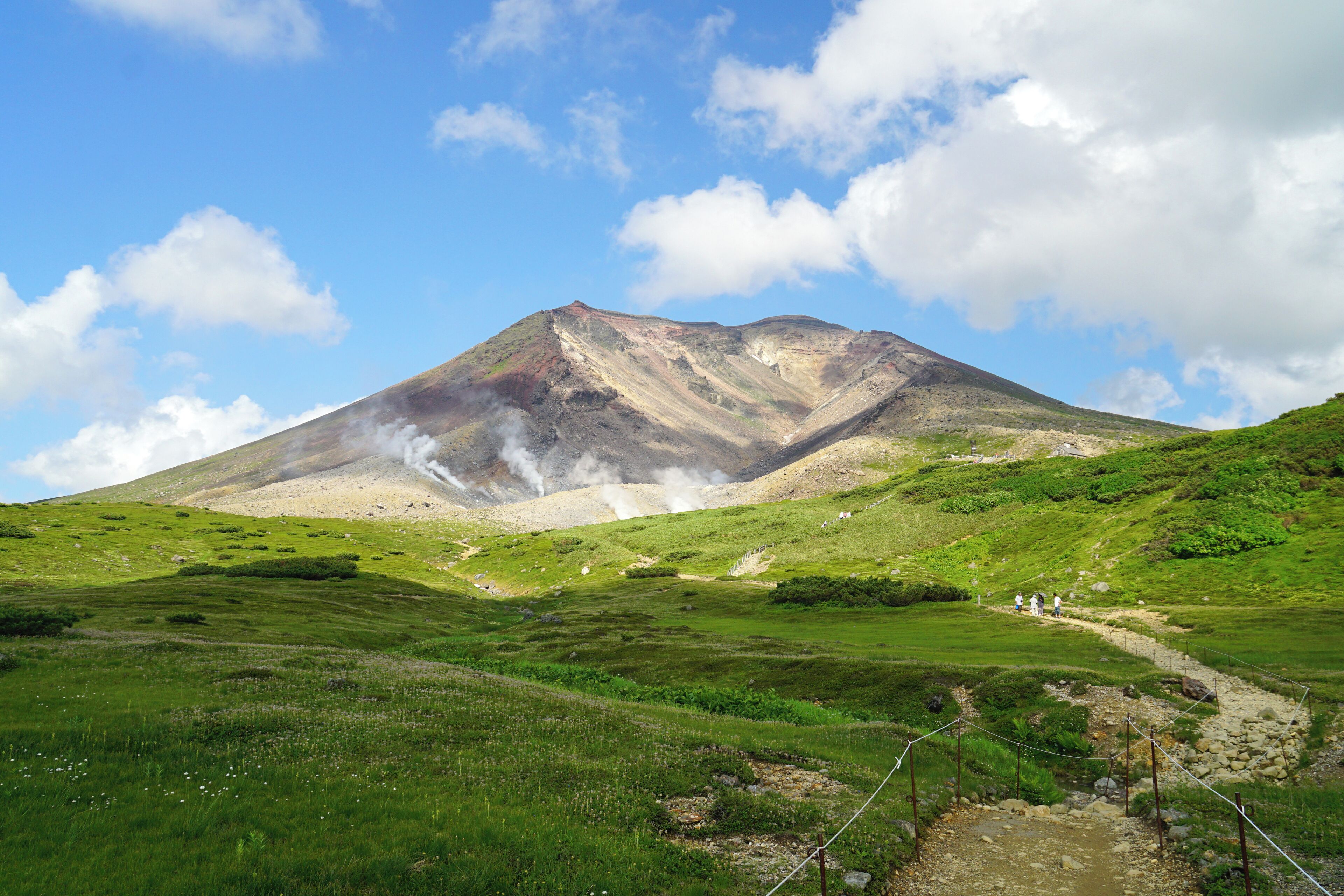 A mountain with a grassy valley and a clear sky.