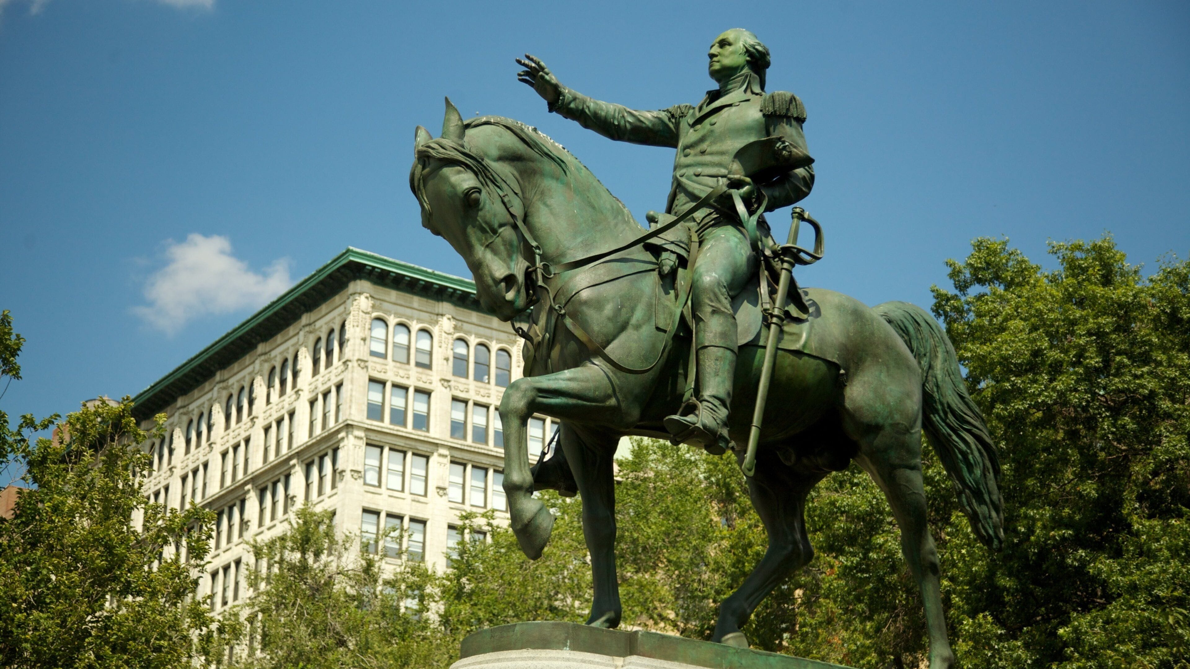 Union Square Park in New York City features a statue of George Washington on horseback among lush trees and vibrant outdoor activity