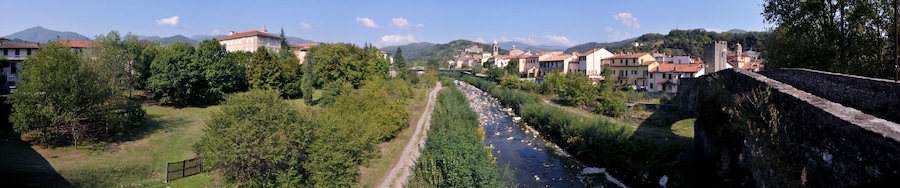 Un río serpentea por una ciudad con edificios y un muro de piedra.
