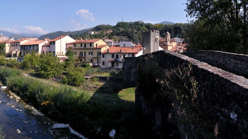 A river flowing through a town with buildings and a stone wall.
