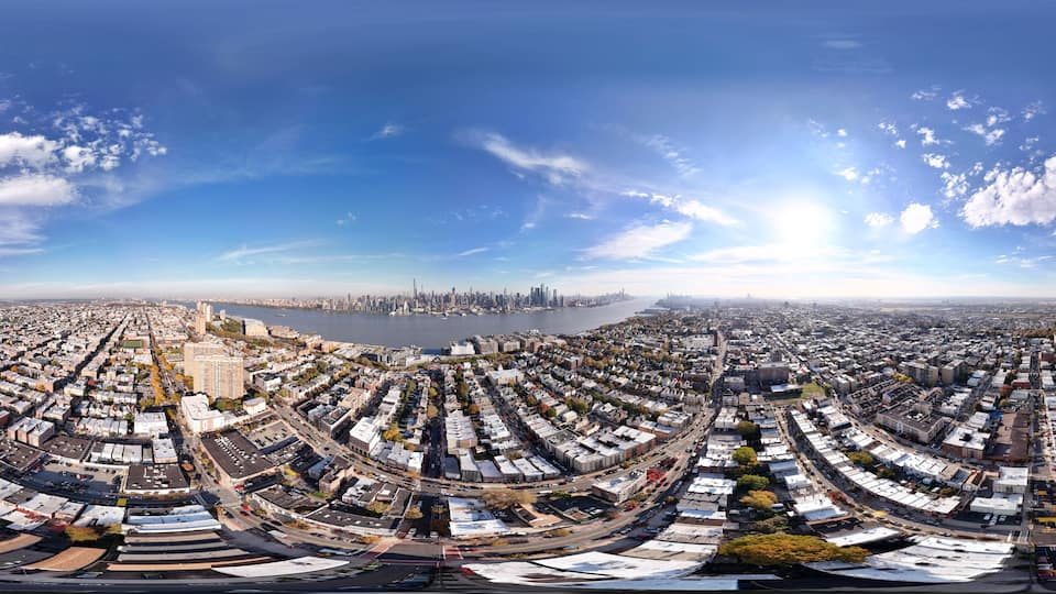 A panoramic view of a city with a river, dense urban area, and a distant skyline.