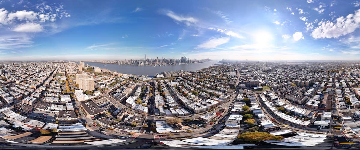 A panoramic view of a city with a river, dense urban area, and a distant skyline.