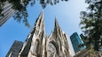 A Gothic cathedral with pointed spires and intricate window designs, surrounded by modern skyscrapers.