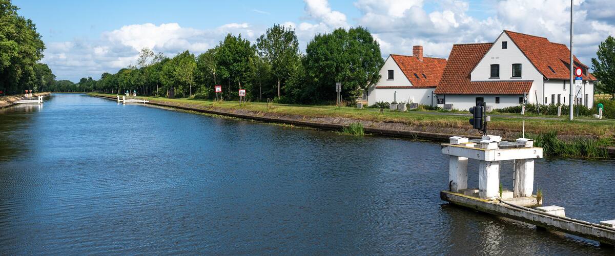 A calm river with a white house and a dock on the right.