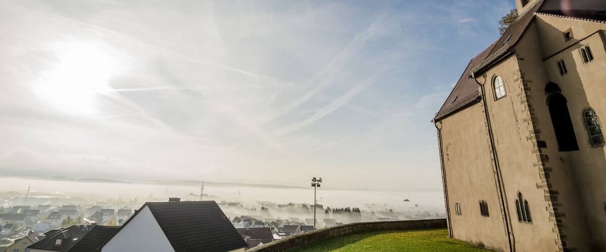 A church with a cross on top, surrounded by a foggy landscape.