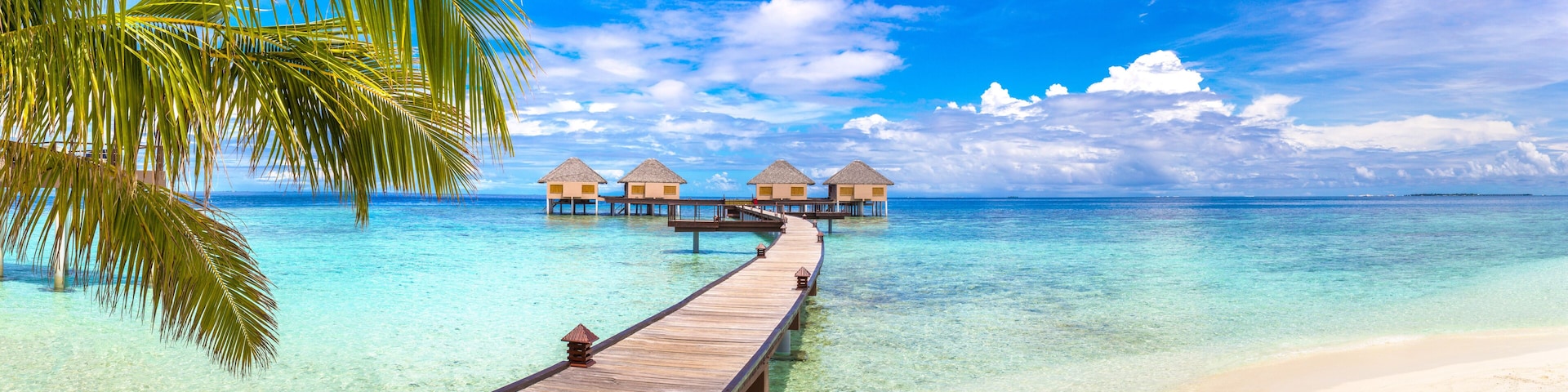 Un muelle de madera que conduce a bungalows sobre el agua en aguas turquesas cristalinas.