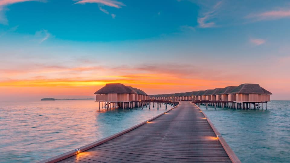 Maldives island sunset. Water bungalows resort at islands beach. Indian Ocean, Maldives. Beautiful sunset landscape, luxury resort and colorful sky. Artistic beach sunset under wonderful sky