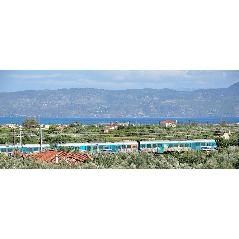 A train traveling through a rural area with mountains in the background.