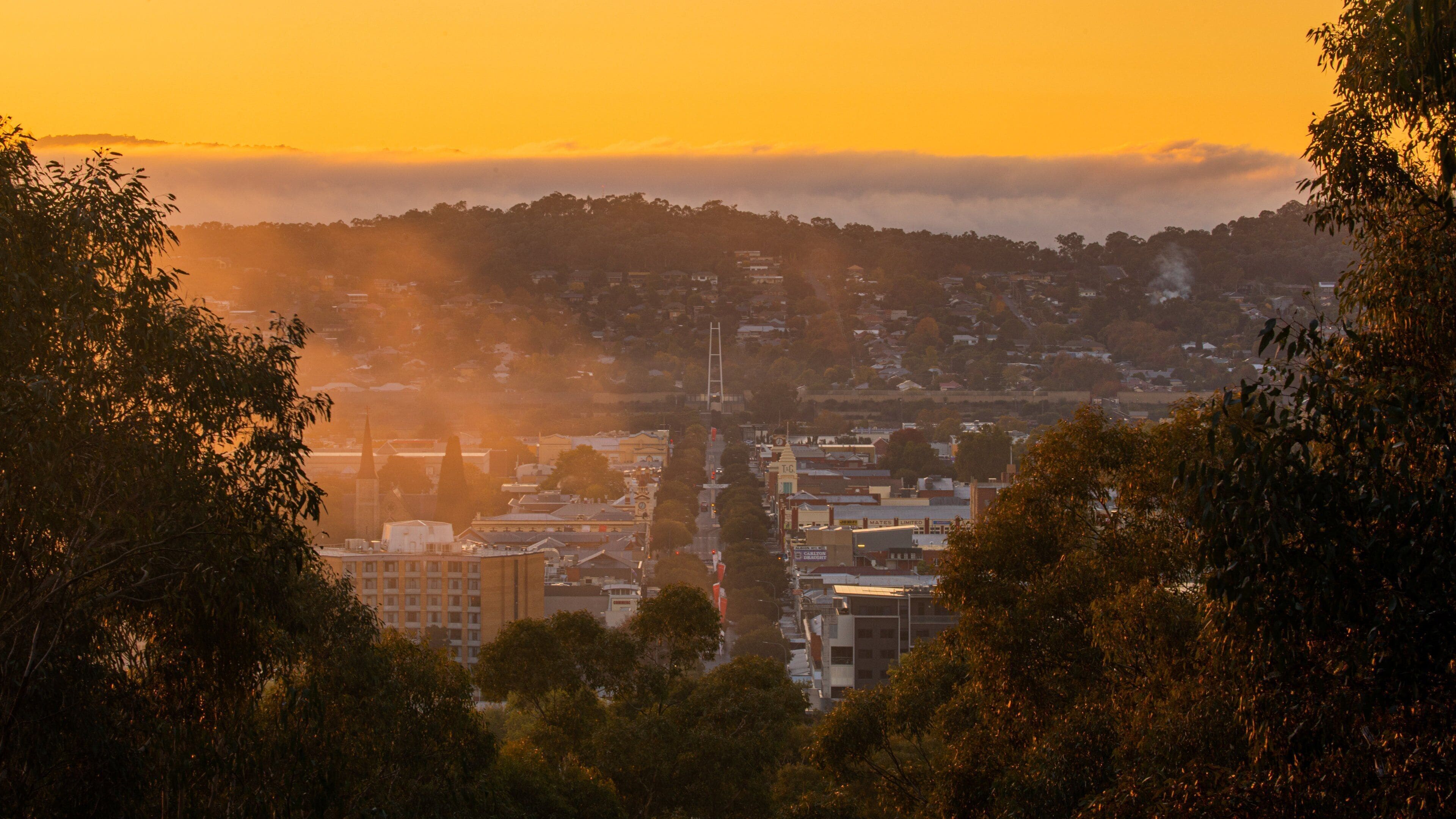 A cityscape at sunset with a prominent church steeple and surrounding buildings.