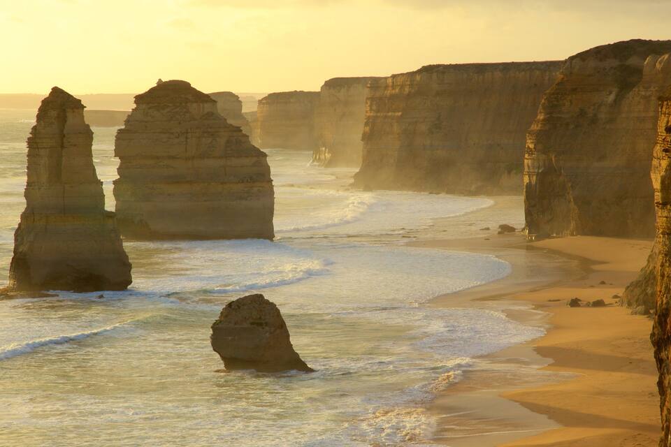A coastal landscape with prominent rock formations and a sandy beach.