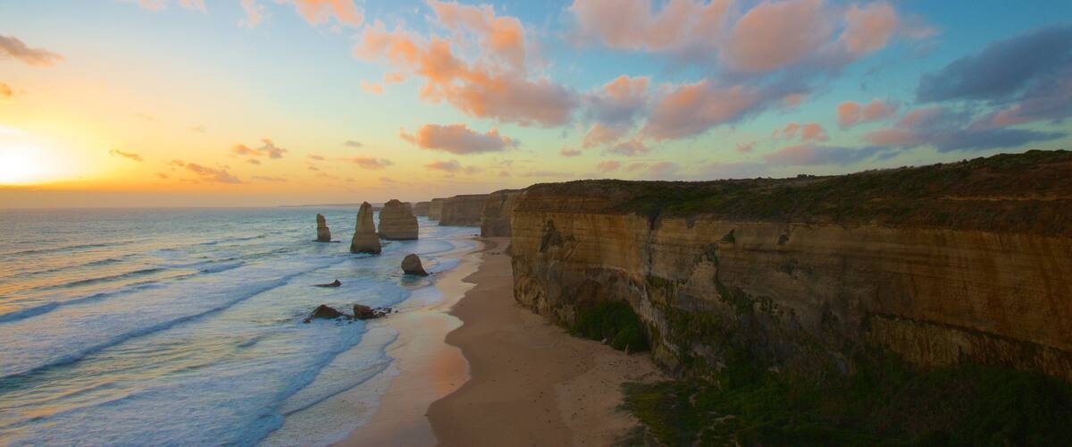 A coastal landscape with cliffs and rock formations at sunset.