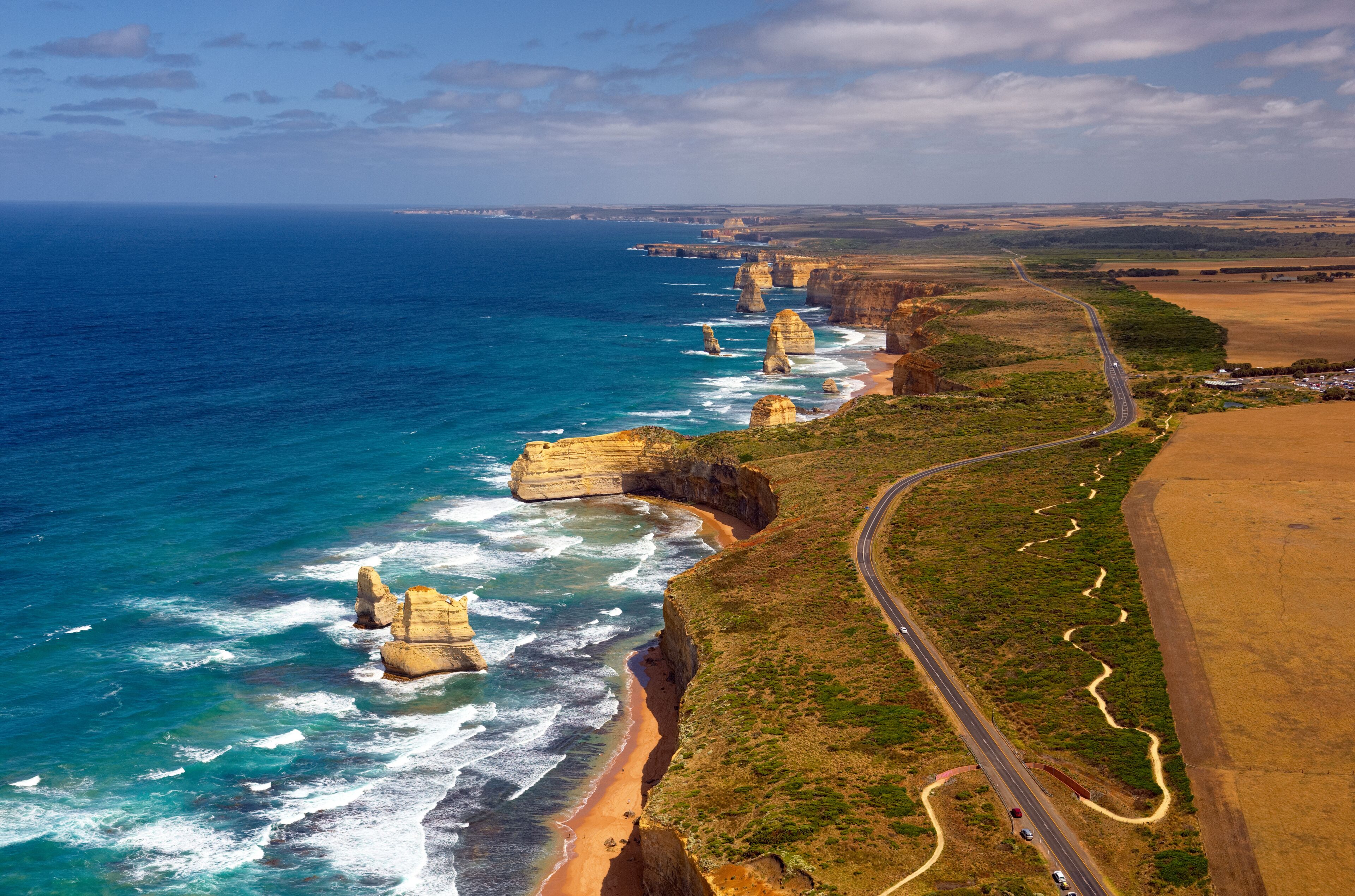 A coastal landscape with cliffs, a winding road, and a beach.