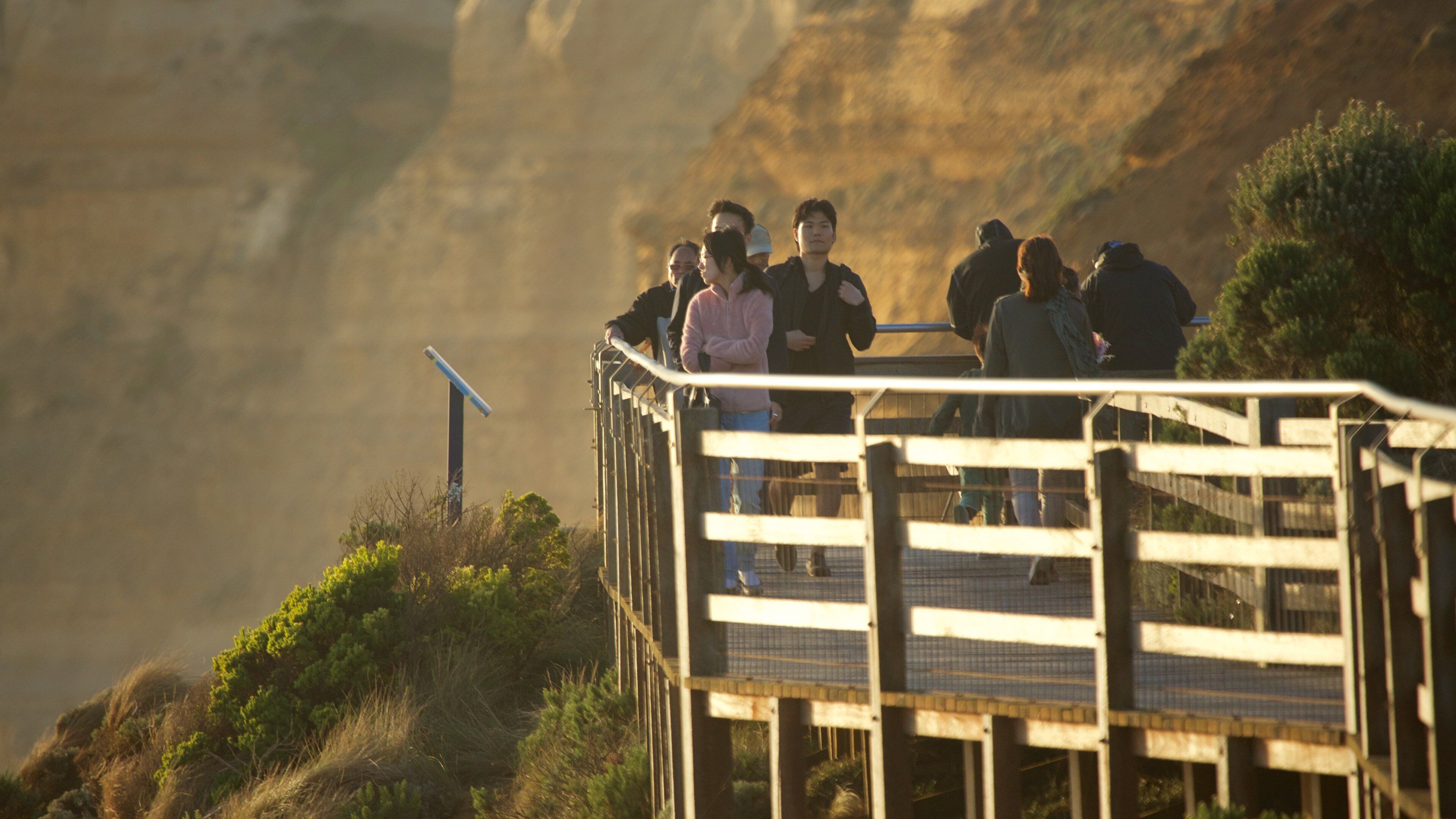 The Twelve Apostles featuring a sunset and views as well as a small group of people
