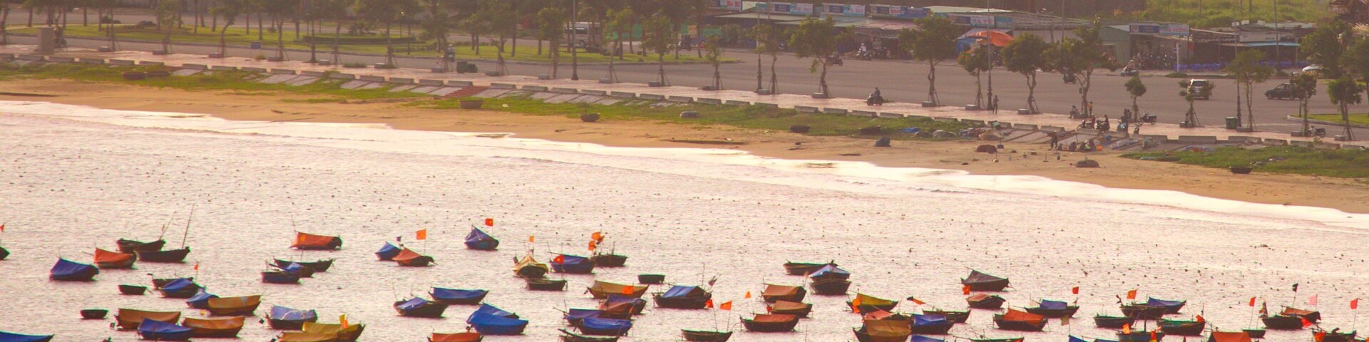 Una playa con numerosas embarcaciones pequeñas ancladas en el agua.