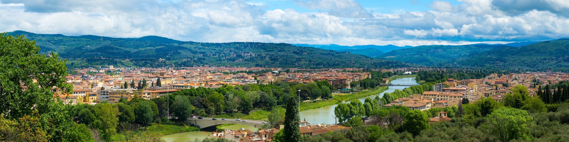 A city with a river, surrounded by mountains and greenery.