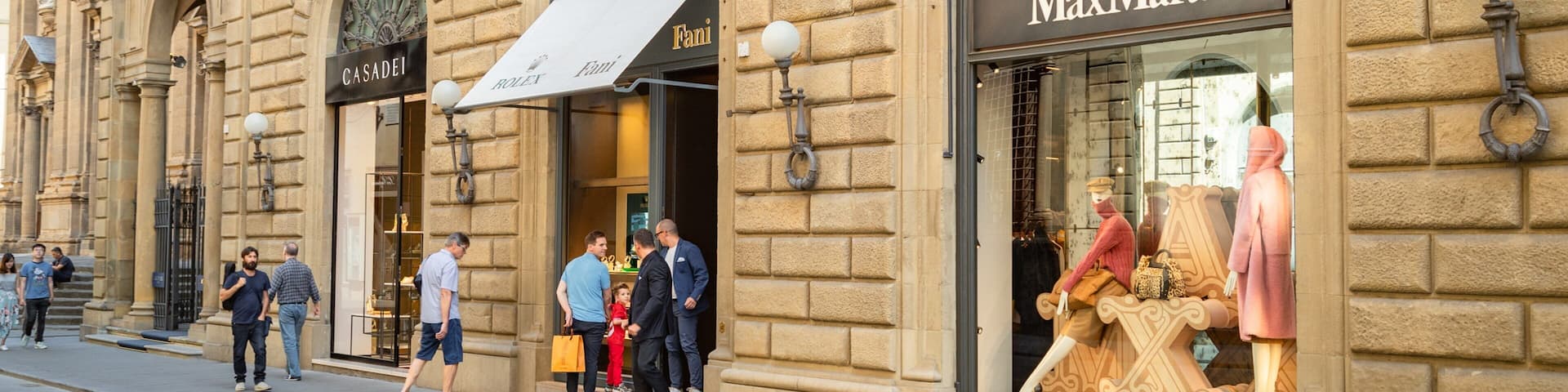 A street with historic buildings, including a MaxMara store and a Fendi store.