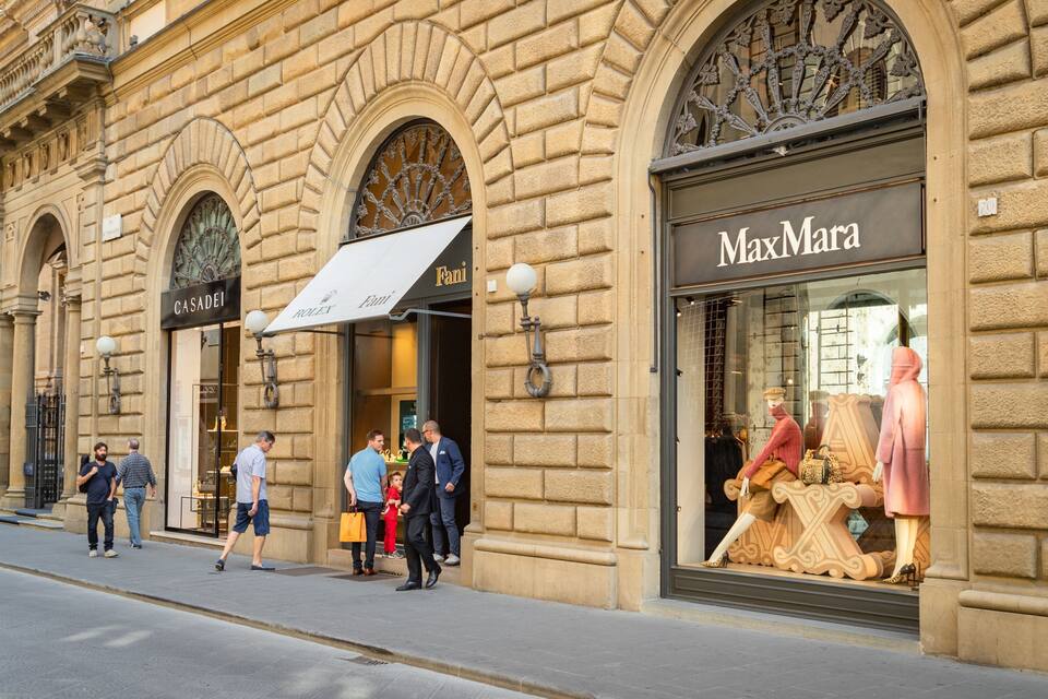 A street with historic buildings, including a MaxMara store and a Fendi store.