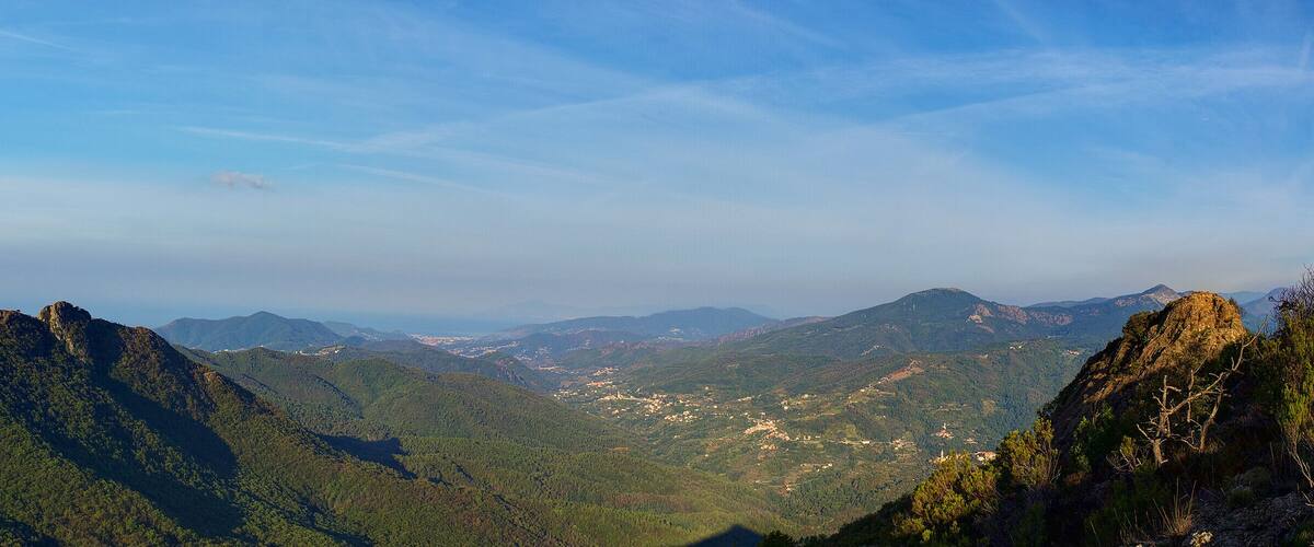 A mountainous landscape with dense forests and a clear sky.