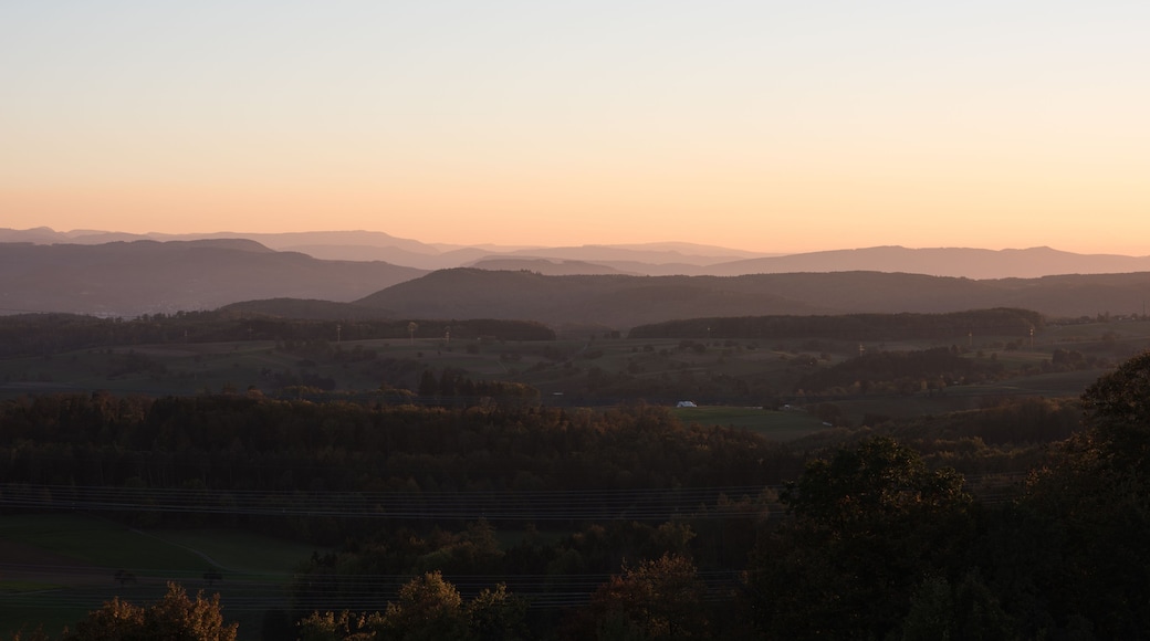 Une vallée aux collines douces, avec une chaîne de montagnes lointaine, au coucher du soleil.