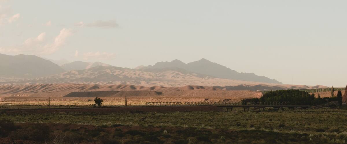 A desert landscape with rolling sand dunes and distant mountains.