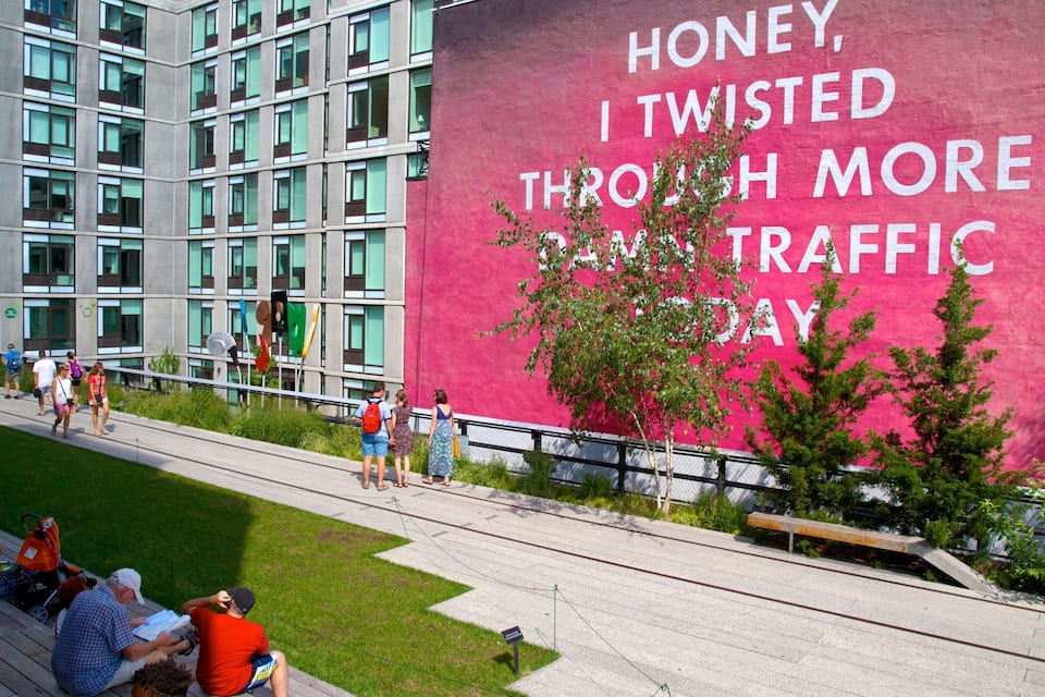 A pink wall with white text, a grassy area, and a modern building with many windows.
