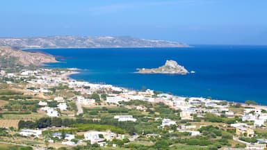 Uma cidade costeira com edifícios, uma praia e uma ilha rochosa no mar.