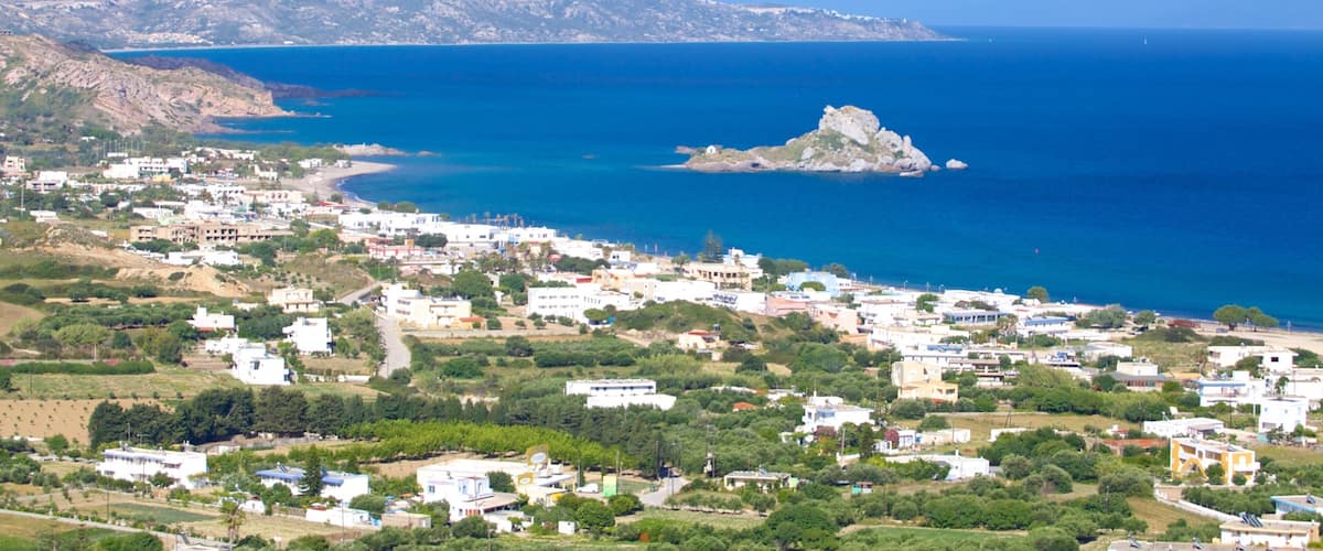 A coastal town with buildings, a beach, and a rocky island in the sea.
