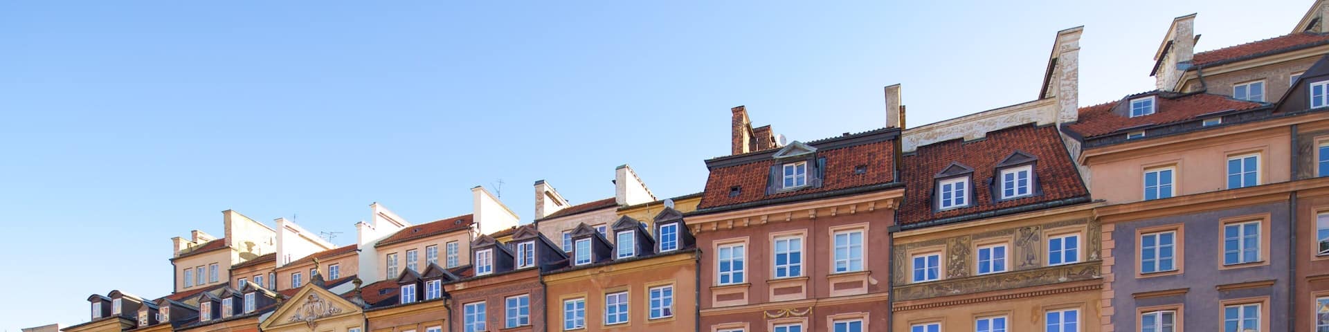 A row of colorful historic buildings with outdoor cafes and tables.