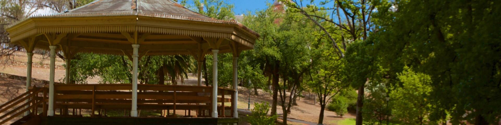 A gazebo in a park with a clear sky and trees.
