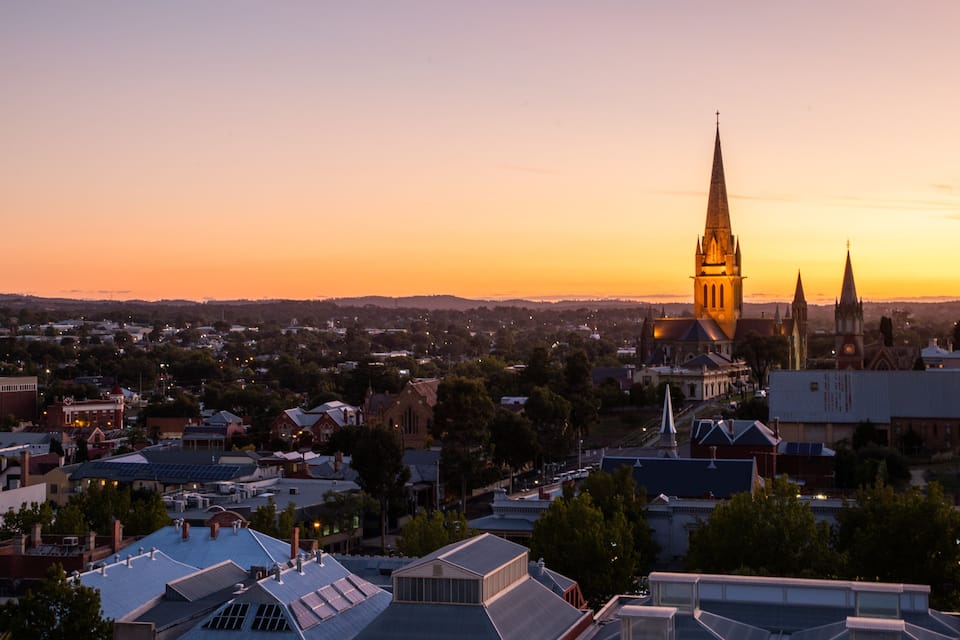 A sunset over a town with prominent church spires and residential buildings.
