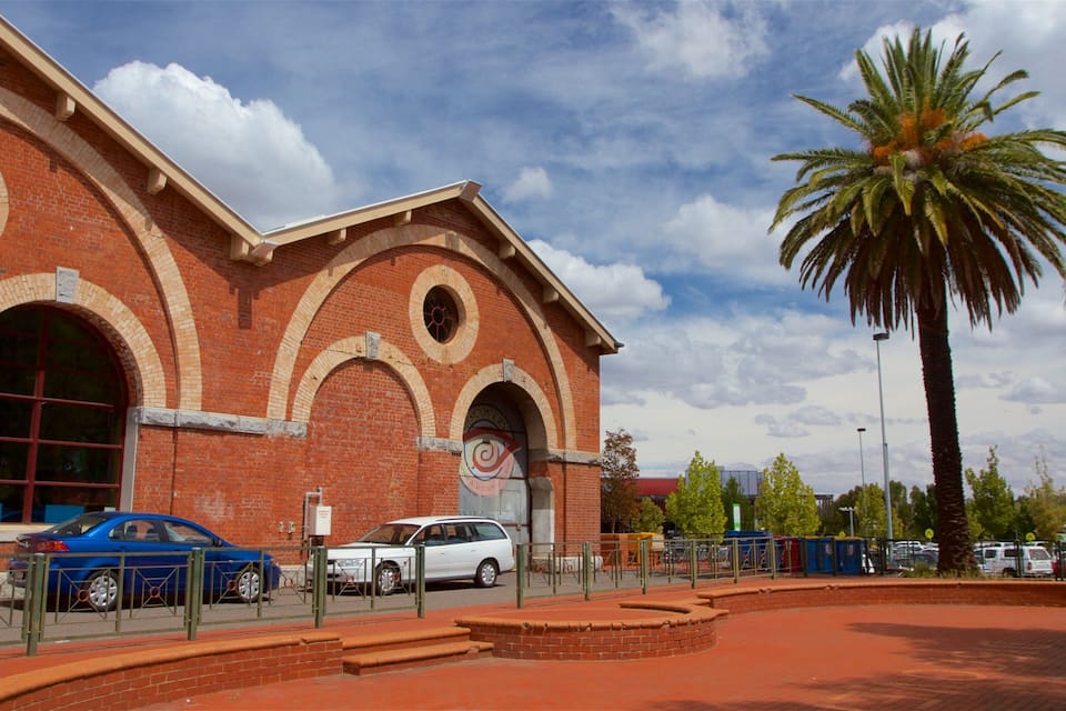 A red brick building with arched windows and a palm tree.