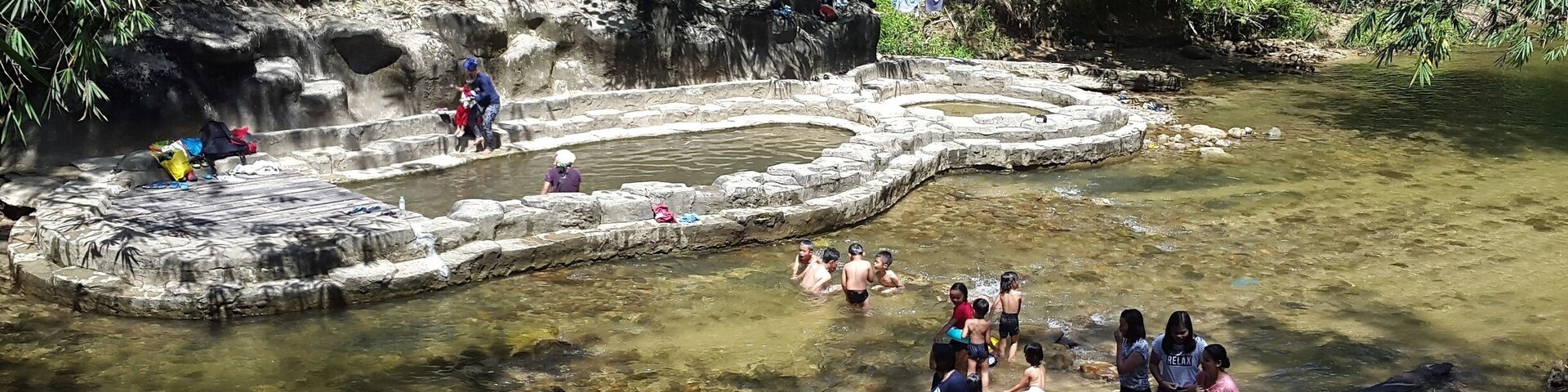 A natural hot spring surrounded by lush greenery and rocky terrain.