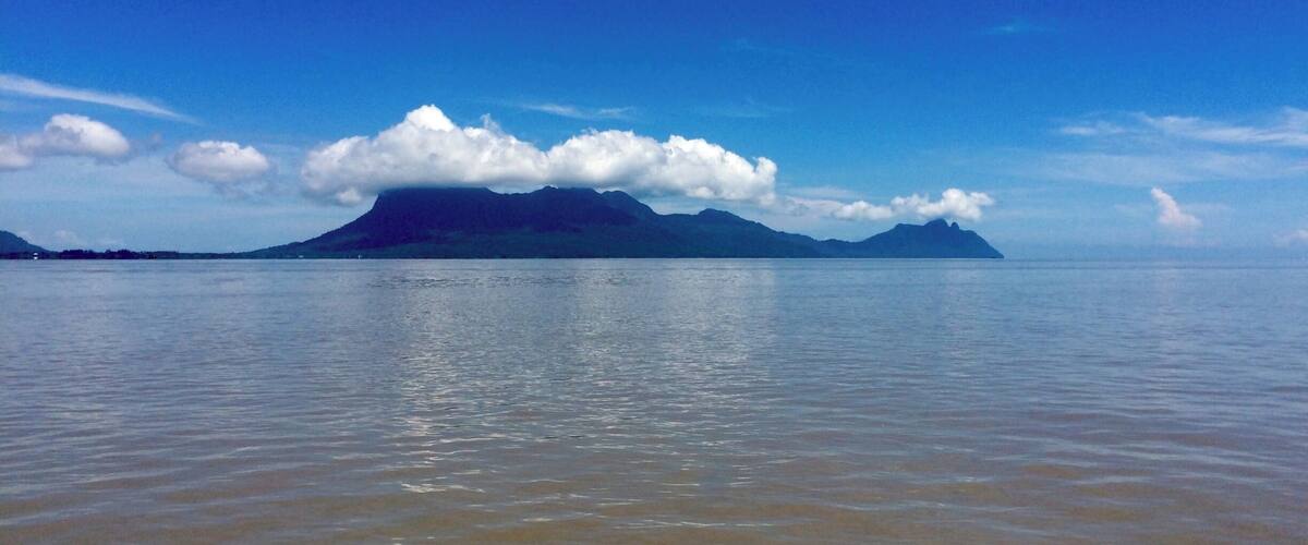 Mar tranquila con una cadena montañosa distante bajo un cielo despejado.