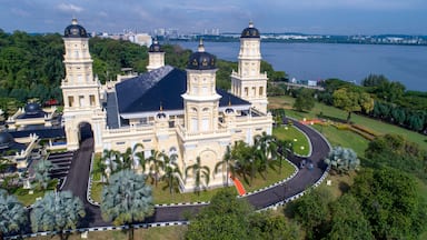 A large, ornate building with two towers and a dome, surrounded by palm trees and a curved road.
