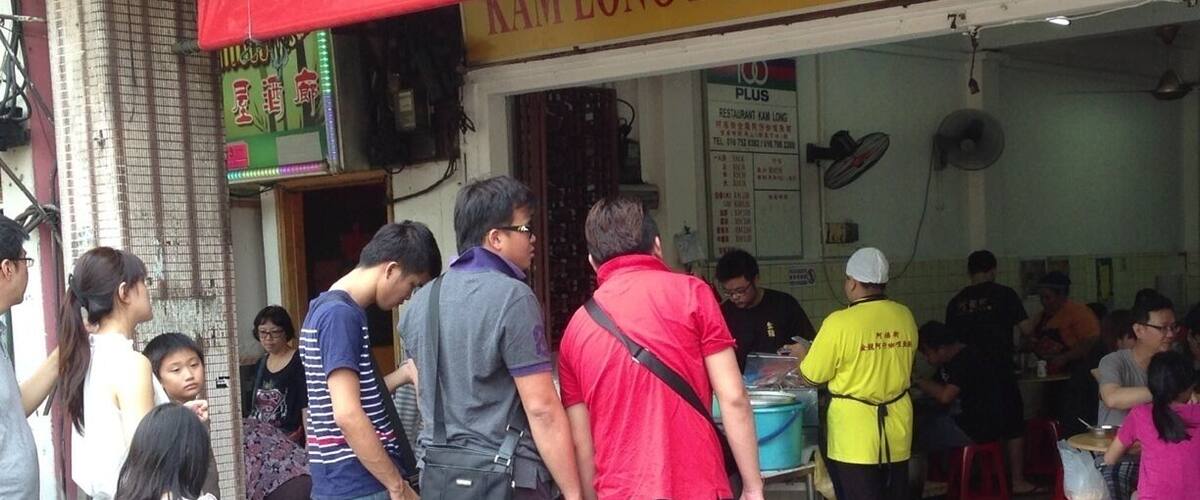 A line of people outside a restaurant with a red sign reading "Jasmine".