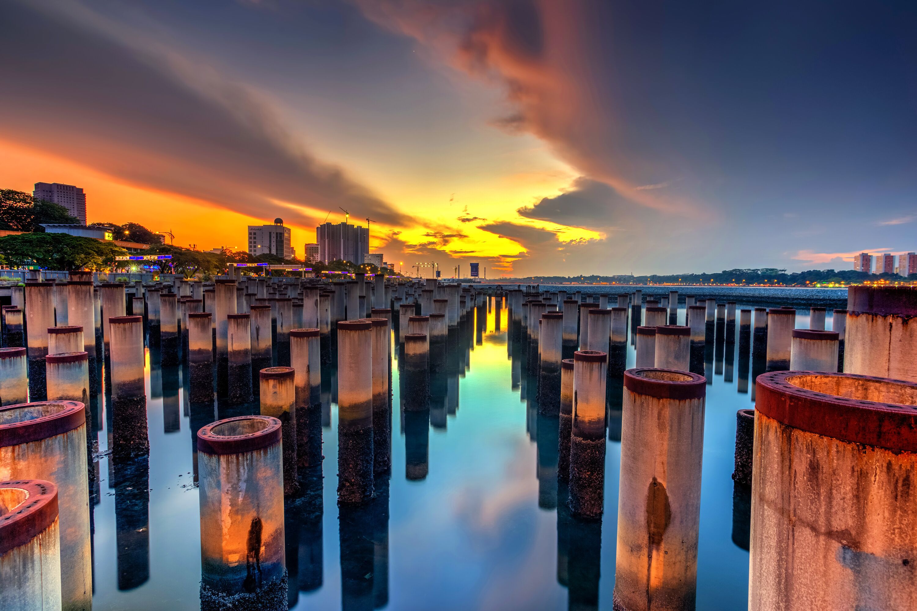 Margem com pilares de concreto e céu ao pôr do sol.
